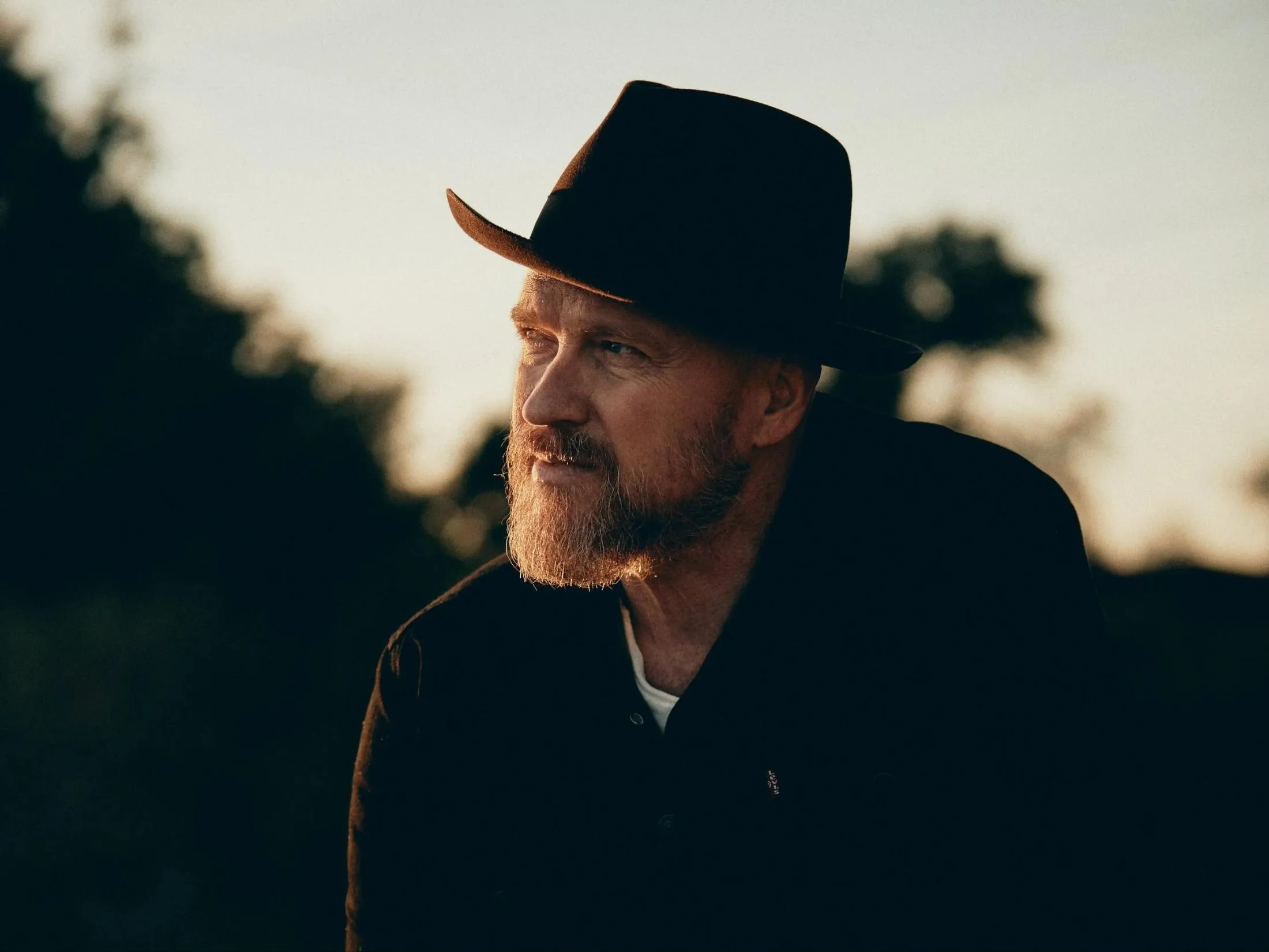 Anthony Skinner in a brown felt hat at golden hour, looking into the distance